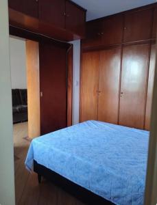 a bedroom with a blue bed with wooden cabinets at Apartamento no Centro de Campo Grande in Campo Grande