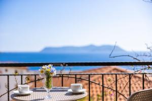 a table with two cups and a vase of flowers on a balcony at Luna Kaş in Kaş