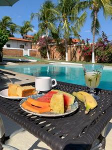 una mesa con una bandeja de fruta y una taza de café en Pousada Vento Brasil Cumbuco en Cumbuco
