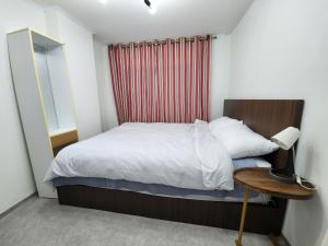 a small bedroom with a bed and a table with a lamp at LaonHajae in Seoul