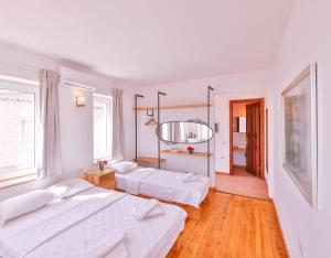 two beds in a room with white walls and wooden floors at Luna Kaş in Kaş