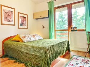 1 dormitorio con 1 cama con edredón verde y ventana en Przestronny apartament z dwoma sypialniami, salonem i kuchnią, otoczony balkonem, z miejscem parkingowym 