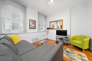 ein Wohnzimmer mit einem Sofa und einem TV in der Unterkunft Apartment 3, 48 Bishopsgate by City Living London in London