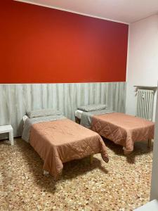 una camera con due letti e una parete rossa di ARCOBALENO by DIMORA CHIC a Novara