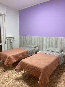 two beds in a room with a purple wall at ARCOBALENO by DIMORA CHIC in Novara