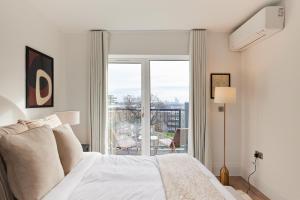 a white bedroom with a bed and a large window at The Wembley Park Corner - Classy 2BDR Flat with Balcony in London