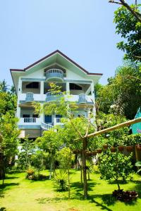 un grand bâtiment blanc avec des arbres devant lui dans l'établissement Greenyard Inn, à Boracay