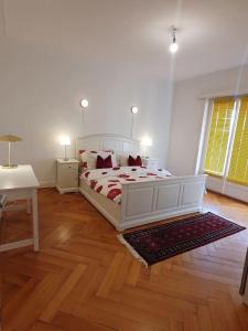 a bedroom with a white bed and a wooden floor at Appartement élégant & ensoleillé in Lausanne