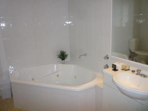 a white bath tub sitting next to a white sink at Bell Tower Inn in Ballarat
