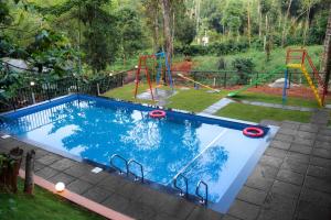 una piscina con tobogán y un parque infantil en TREE6 WAYANAD, en Vythiri