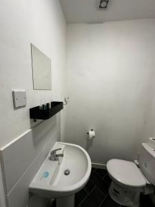 a white bathroom with a toilet and a sink at Blackwood Residence in Accrington