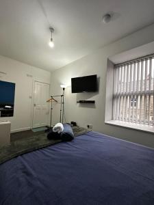 a bedroom with a large blue bed with a flat screen tv at Blackwood Residence in Accrington