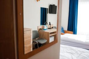 1 dormitorio con cama, silla y espejo en Hotel Kliper, en Władysławowo