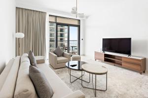 uma sala de estar com um sofá e uma televisão em Silkhaus Marina View with Tower's Private Beach em Dubai