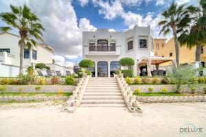 una casa en la playa con escaleras y palmeras en Seaside 5BR Villa with Assistant's Room and Beach Access on Palm Jumeirah by Deluxe Holiday Homes, en Dubái