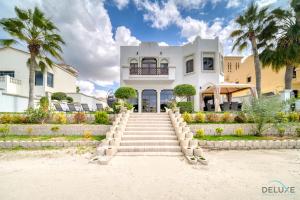 a house on the beach with stairs and palm trees at Seaside 5BR Villa with Assistant's Room and Beach Access on Palm Jumeirah by Deluxe Holiday Homes in Dubai