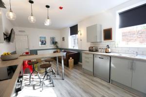 cocina con armarios blancos, mesa y sillas en Contractors Dream 7 bed 7 ensuite en Birkenhead