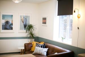 sala de estar con sofá de cuero marrón y 2 ventanas en Contractors Dream 7 bed 7 ensuite en Birkenhead
