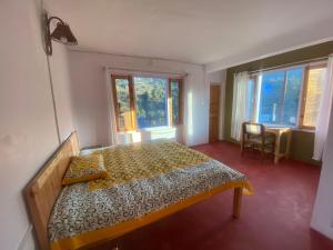 ein Schlafzimmer mit einem Bett in einem Zimmer mit Fenstern in der Unterkunft Brook Cottage in Champawat