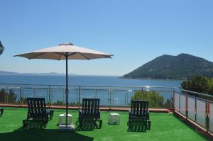 eine Terrasse mit Stühlen, einem Sonnenschirm und dem Meer in der Unterkunft Hostal Solymar in Louro
