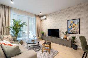 uma sala de estar com um sofá e uma televisão em Mediteranian 1BR in Nusco City em Bucareste