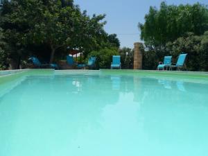 a large swimming pool with blue chairs and trees at Masseria Pugliese Farm in Ostuni