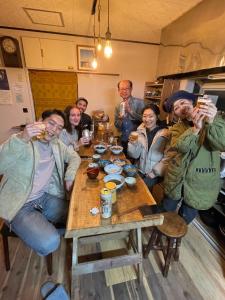 un grupo de personas sentadas en una mesa bebiendo cerveza en ゲストハウス千倉のおへそ, en Chikura