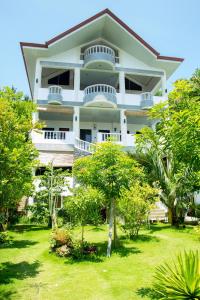 un grand bâtiment blanc avec des arbres devant lui dans l'établissement Greenyard Inn, à Boracay