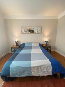 ein blau-weißes Bett in einem Zimmer mit 2 Tischen in der Unterkunft appartement de 50m2 grand et spacieux avec jardin in Viry-Châtillon