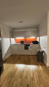 eine leere Küche mit weißen Schränken und Hartholzboden in der Unterkunft Luxury 1-Bed Apartment in the heart of Leicester in Leicester