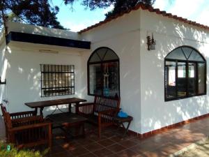 a small white house with benches and a table at En Resort Fincas Las Dunas dos Chalets con jacuzzis en primera linea de playa , uno de 4 dormitorios y otro de 2 dormitorios, Llama al Seiscientos veintisiete Cuatrocientos diecisiete Trescientos noventa y ocho in Rota
