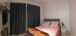a bedroom with a bed with pink pillows at Ap no centro com ar condicionado e Garagem Coberta in Cascavel
