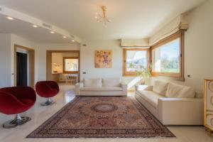 sala de estar con sofá blanco y sillas rojas en Villa Vescovado casa vacanza en Brusaporto