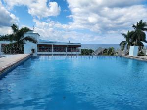 a large swimming pool with the ocean in the background at Hotel 39 Jamaica in Montego Bay