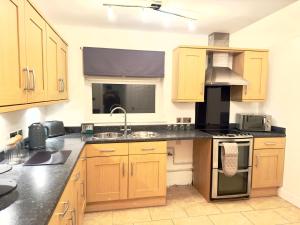 a kitchen with wooden cabinets and a stove top oven at Rooms Near Me - Worcester, Sky Tv, Free Double Parking in Worcester