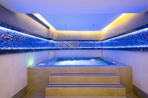 a jacuzzi tub in a room with blue tiles at Anemon Kent Mersin Otel in Çiftlikköy
