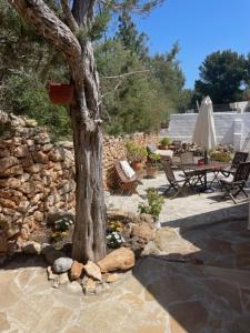 un árbol y una pared de piedra con mesa y sillas en retreat studio en Santa Eularia des Riu