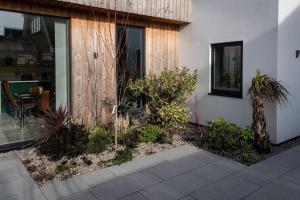 a garden outside of a house with plants at Coastal Courtyard with Hot Tub, Greatstone in Greatstone