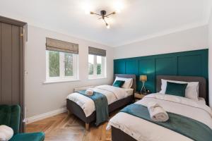 two beds in a bedroom with green headboards at Spacious Stunning Flat near Heathrow and Central London in Hounslow