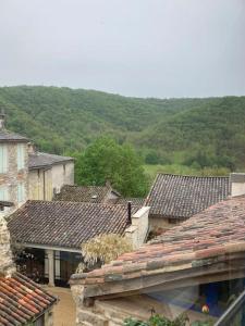 un grupo de techos de casas con colinas en el fondo en La nuit de la chouette, en Bruniquel