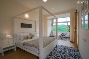 a bedroom with a canopy bed and a balcony at EKOSTAY I Pearl House Villa I 360 Degrees Tea Estate in Ooty