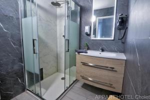 y baño con ducha, lavabo y espejo. en Appart' hôtel Cholet, en Cholet