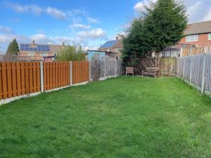 a backyard with a wooden fence and a green yard at Stunning 3 bedrooms house with Garden and Free Parking in Barnsley