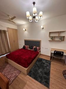 a bedroom with a large red bed with a chandelier at Palm Studio & looms in Noida