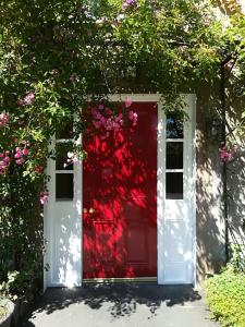 a red door with a window and pink flowers at Ballylagan Organic Farm in Straid