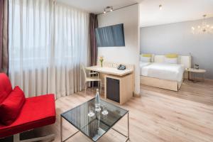 um quarto de hotel com uma cama e um sofá vermelho em Abba Berlin Hotel em Berlim