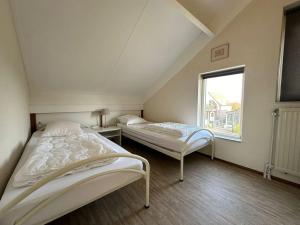Dos camas en una habitación con ventana. en Crox Houcke 24*, en Nieuwvliet
