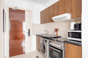 eine Küche mit einer Waschmaschine und einer Mikrowelle in der Unterkunft Silkhaus Luxury Studio in a Residential Neighborhood in Dubai