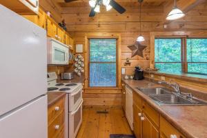 una cucina con armadi in legno e un piano cottura bianco con forno di Firefly Lodge Private Log Cabin with Mountain Views! a Black Mountain