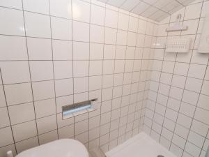a white tiled bathroom with a toilet in it at The Artists Cabin in Herne Bay